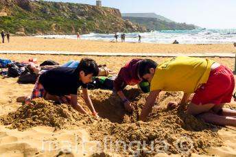 Vedoucí a studenti si hrajou na pláži v písku