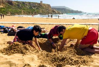 Vedoucí a studenti si hrajou na pláži v písku